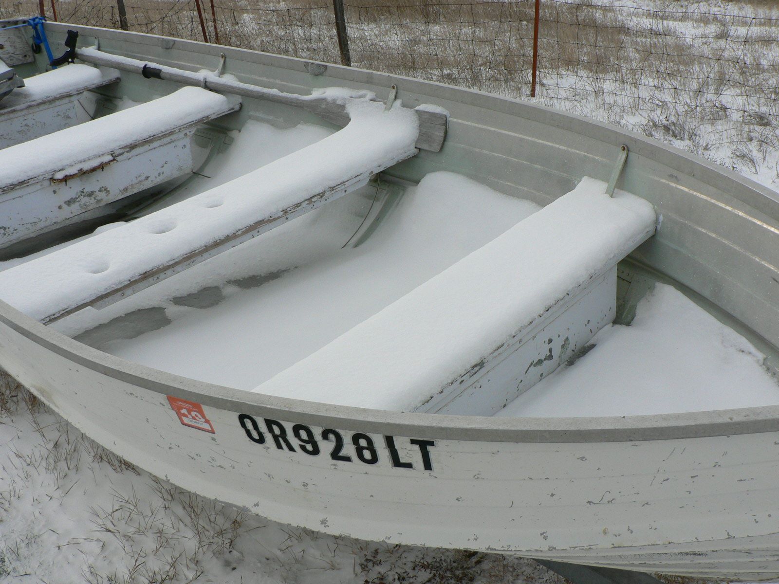 A boat with the license plate or928lt is covered in snow