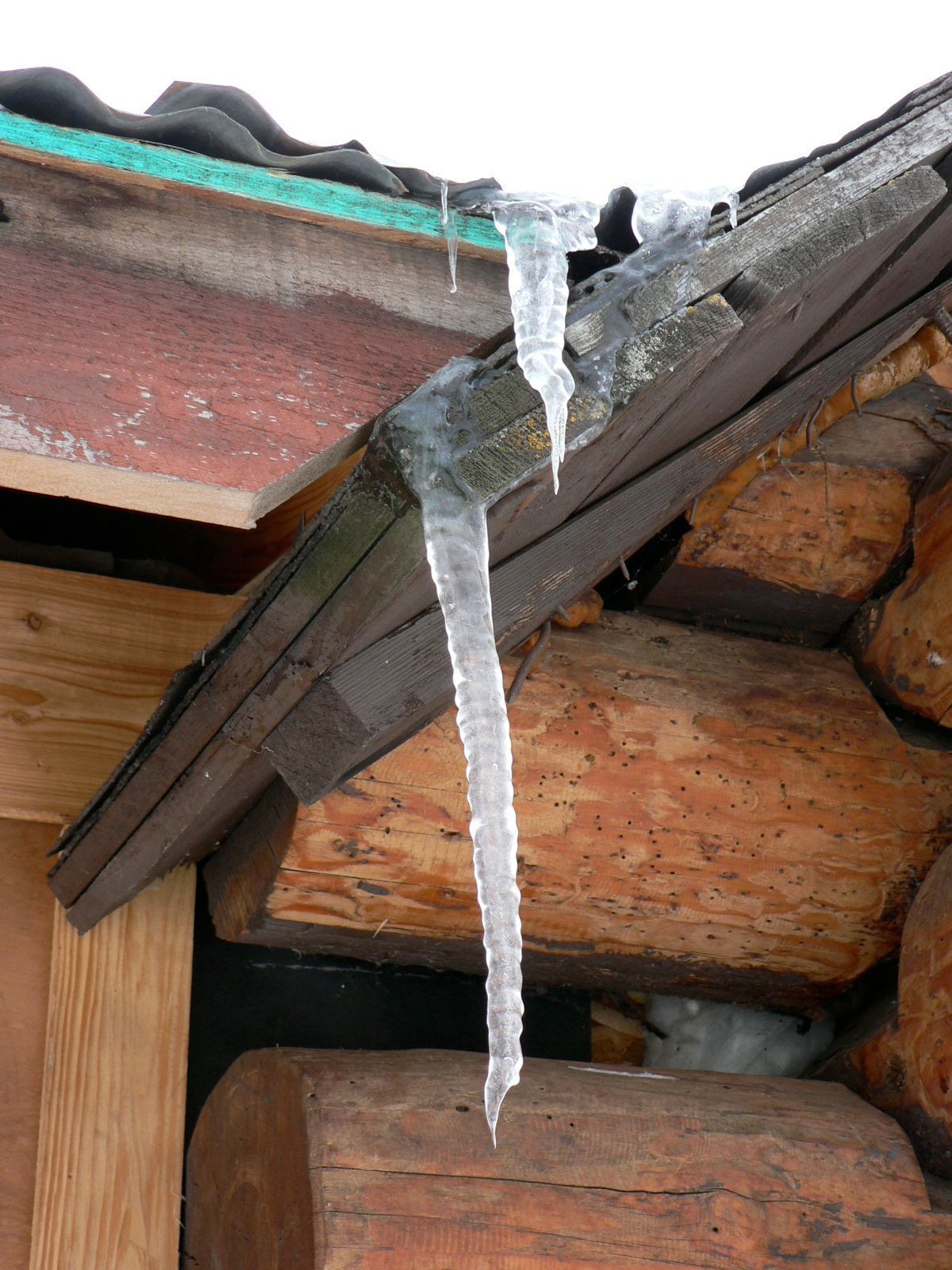 Icicles are hanging from the roof of a log cabin