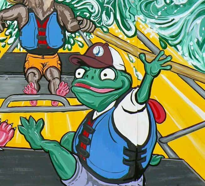 A frog wearing a hat is sitting in a boat