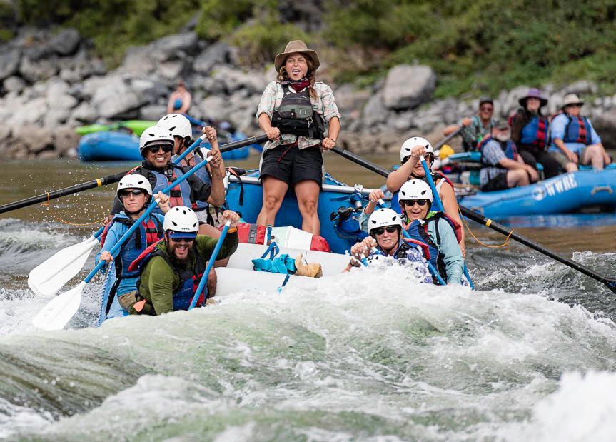 A Group of People Are Rafting Down a River with Blue Raft