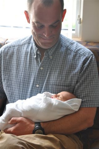 A man is holding a newborn baby in his arms.