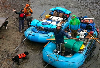 A man in a cowboy hat is standing in front of two rafts