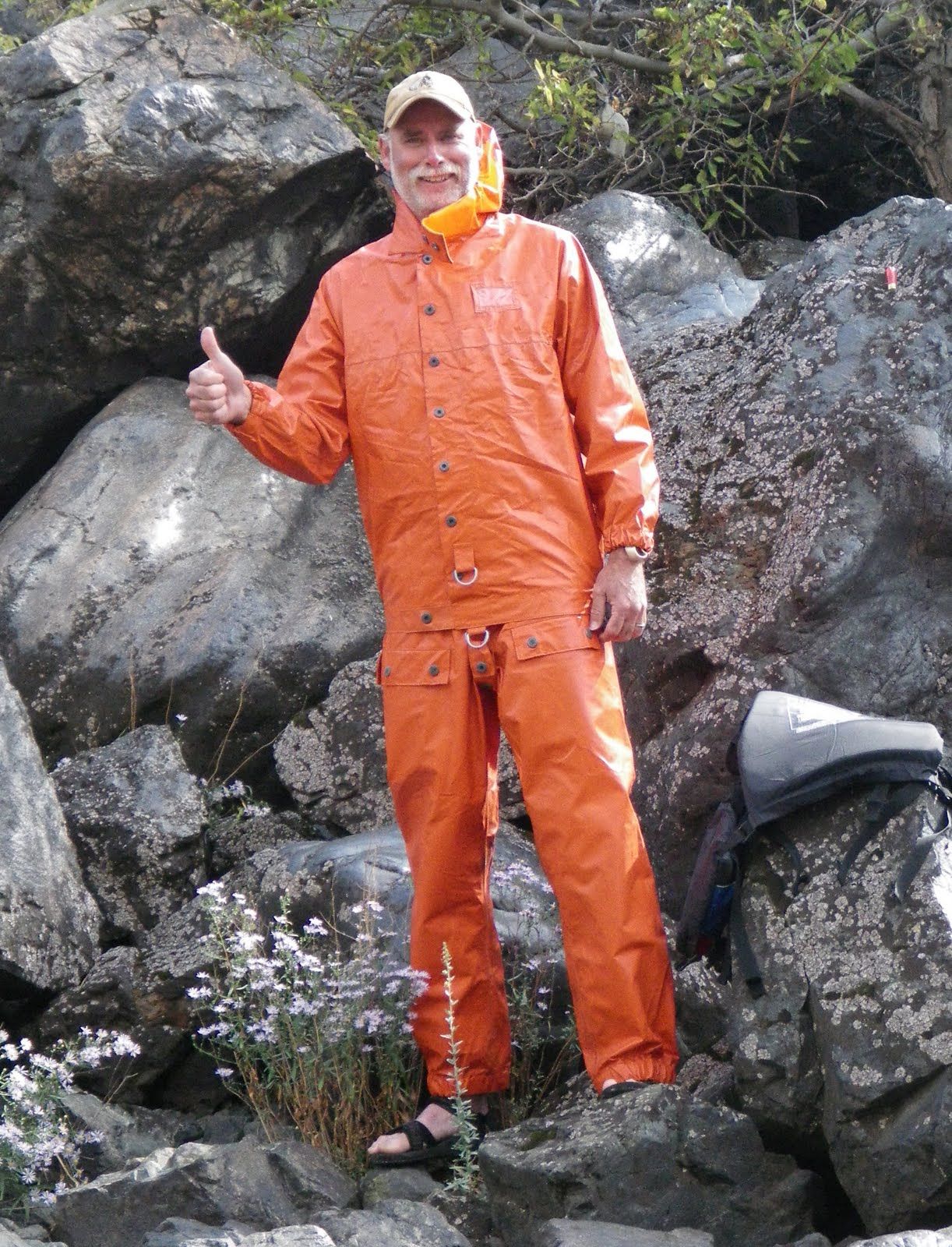 A man in an orange rain suit is giving a thumbs up