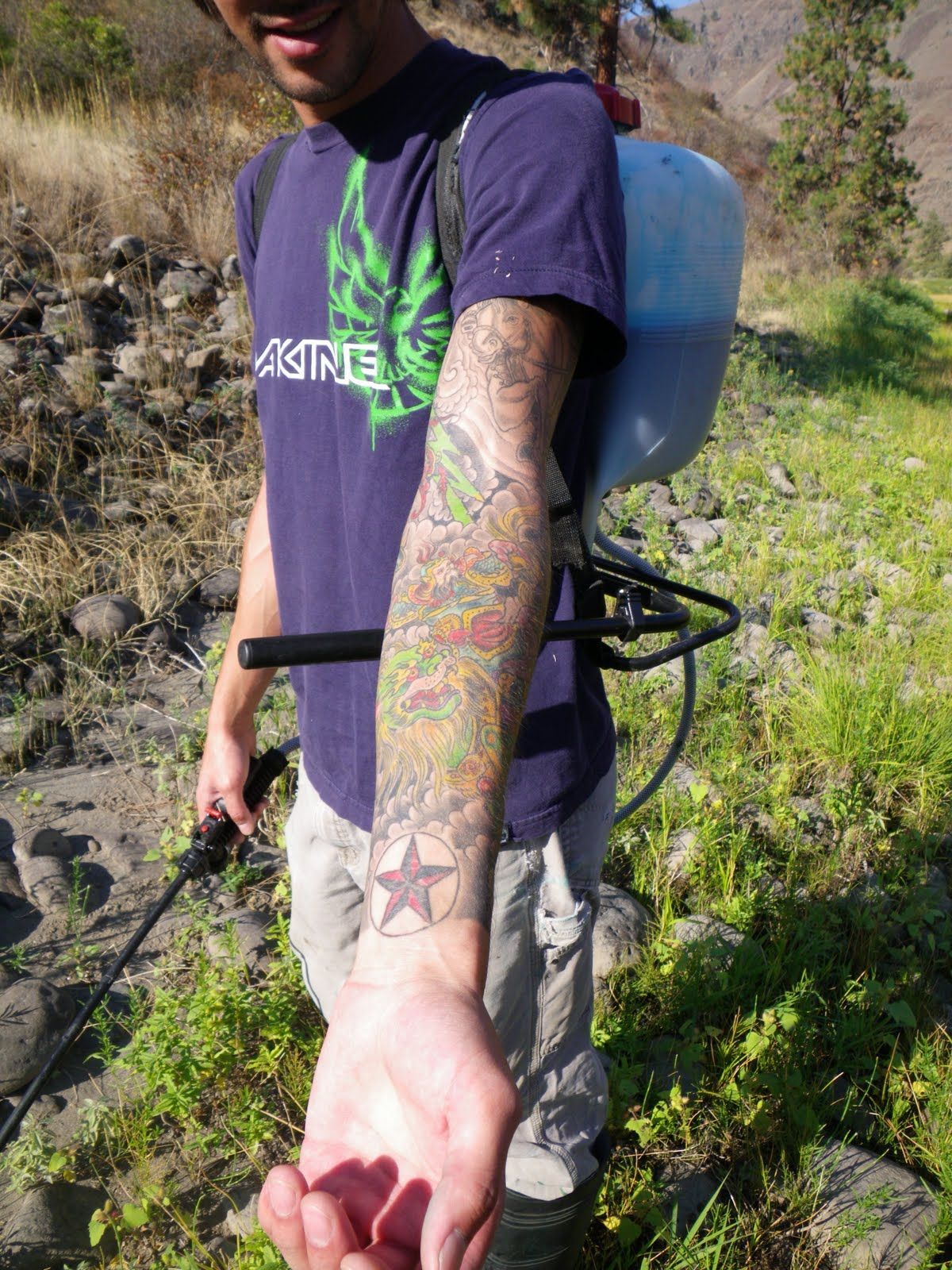 A man in a purple shirt has a tattoo on his arm