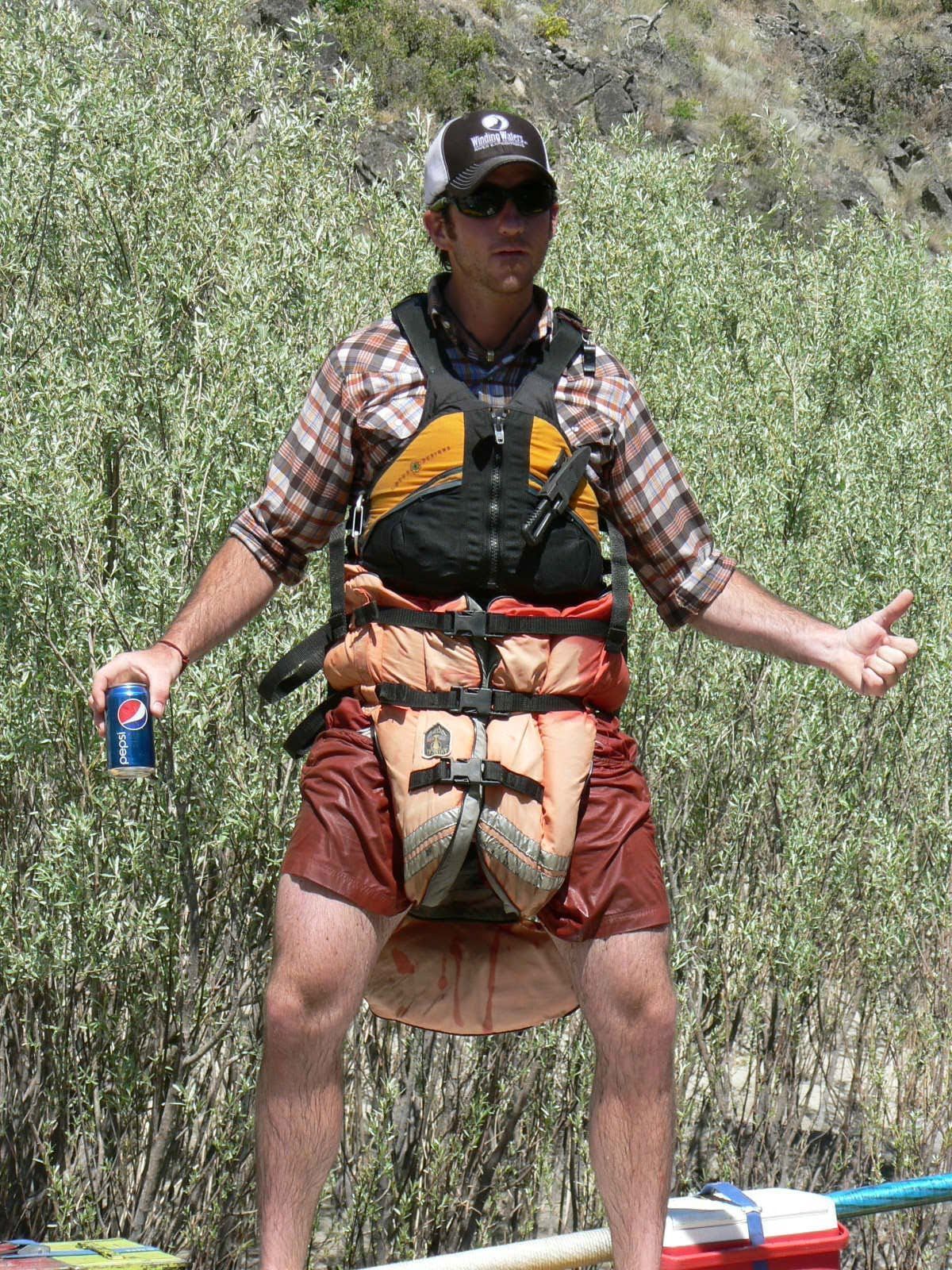 A man in a life jacket is holding a can of pepsi