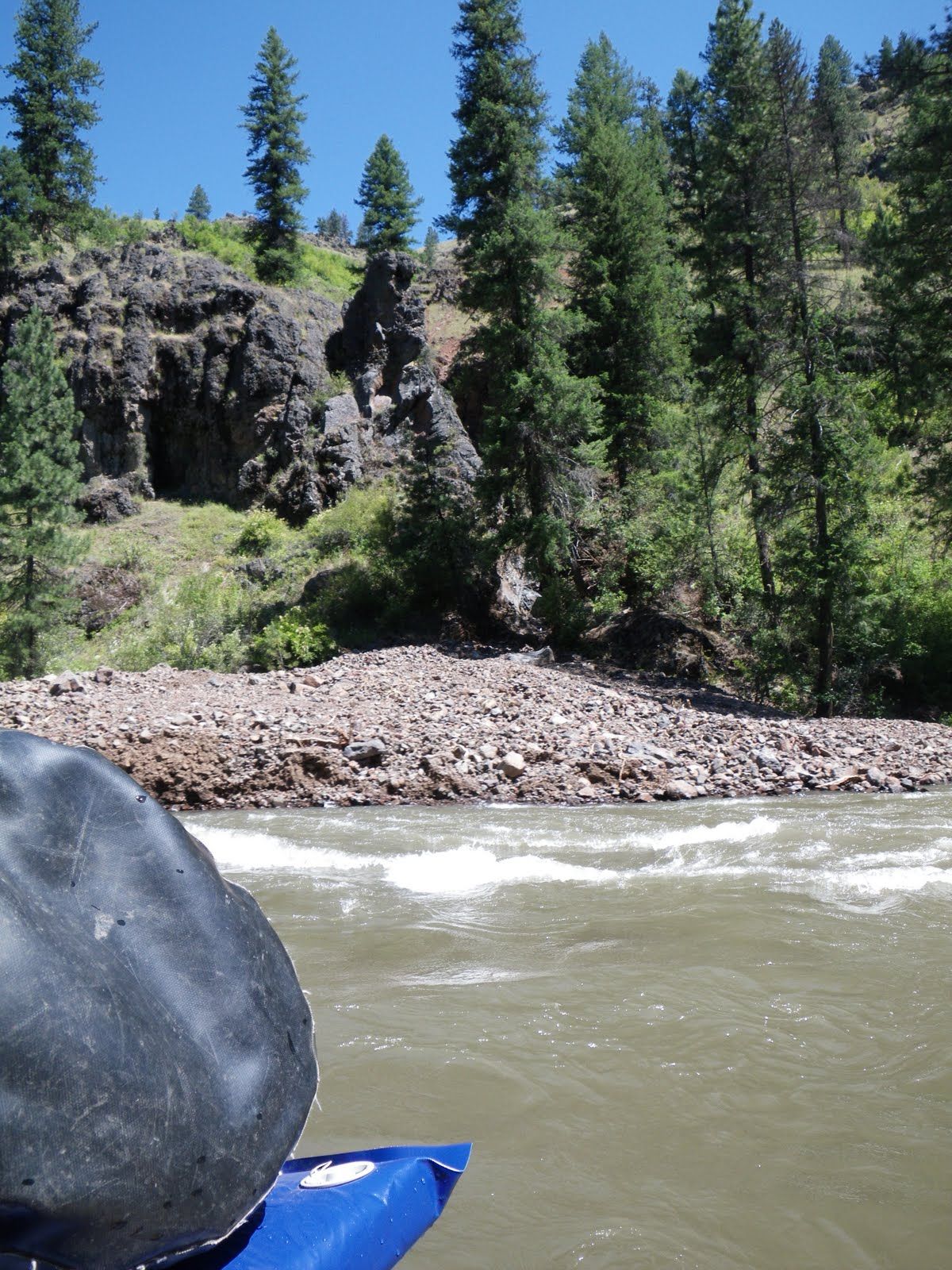 A person in a blue kayak looking out over a river
