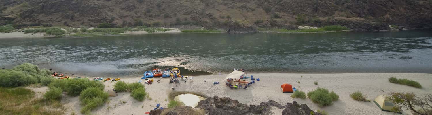 A group of people are camping on the shore of a lake.