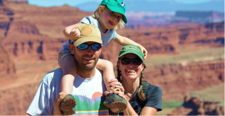 A man and woman are holding a child on their shoulders.