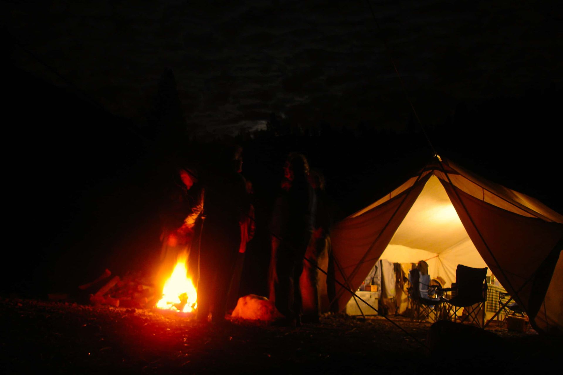 A group of people standing in front of a tent at night