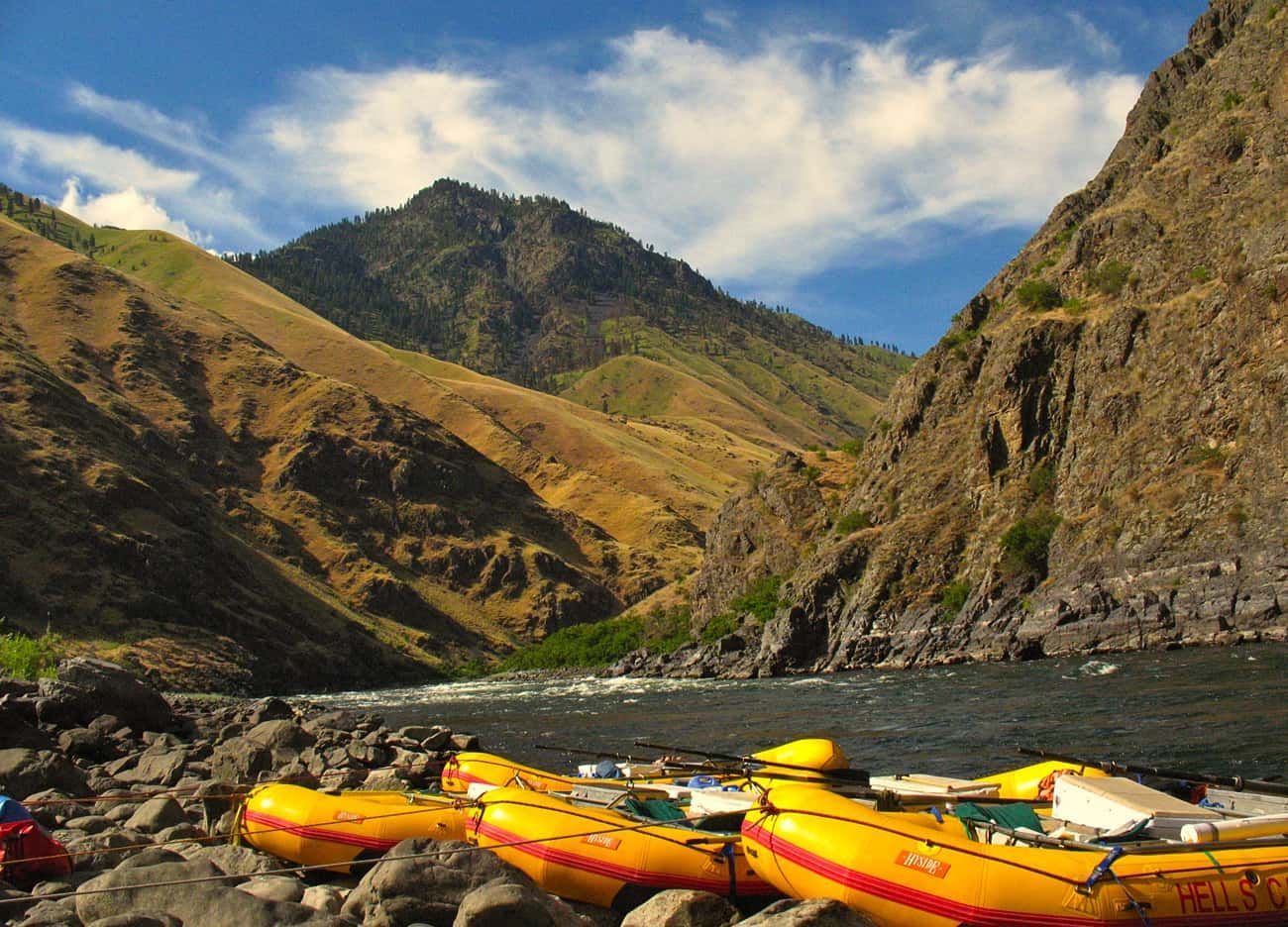 Yellow rafts rest along a river bank in a canyon