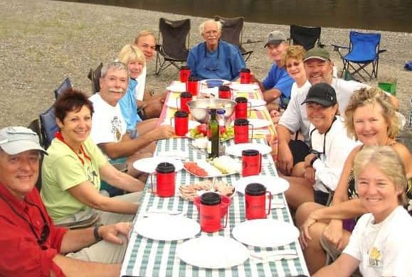 A group of people sitting around a table with plates and cups