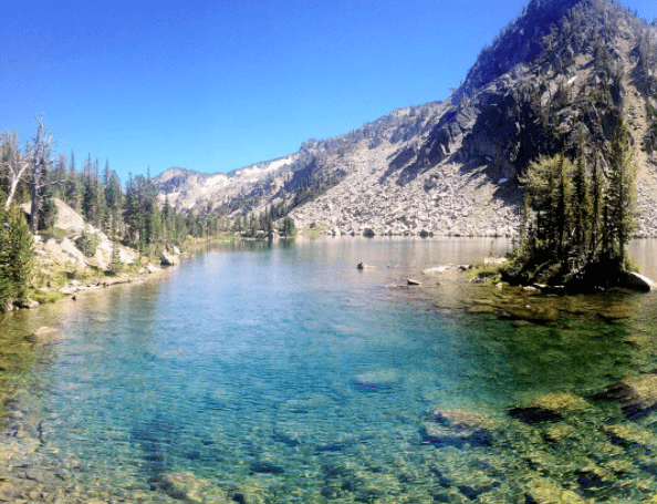 Lake Surrounded by Mountains and Trees on A Sunny Day
