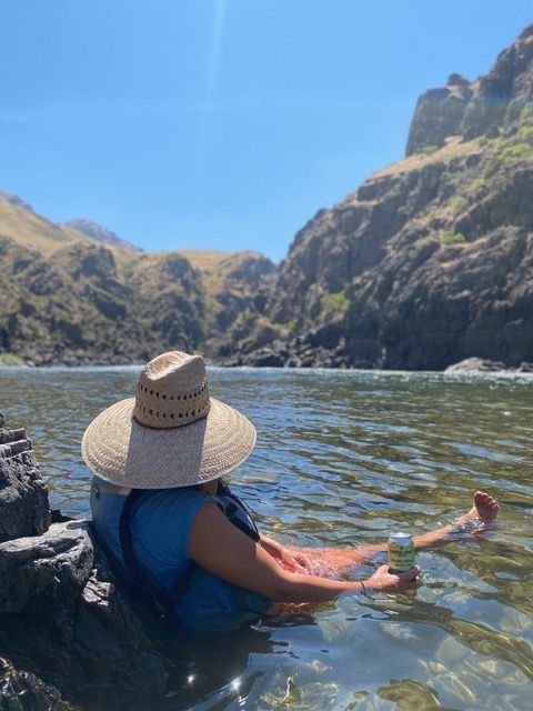 A Woman in A Straw Hat is Sitting in A River