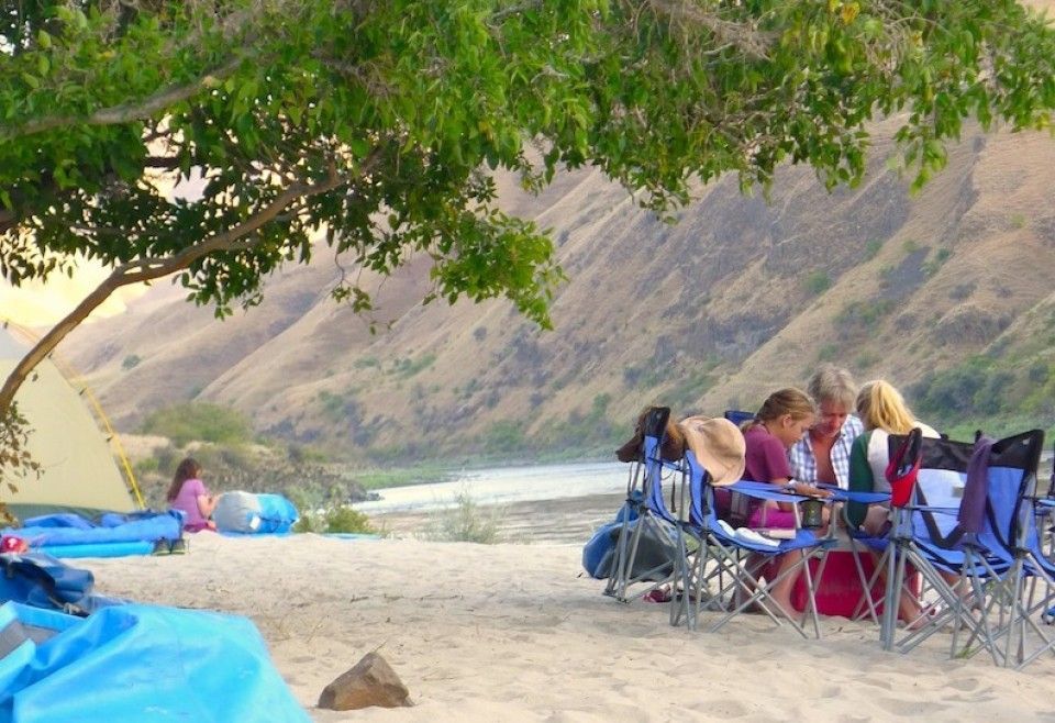 A Group of People Sitting at A Table Near the River