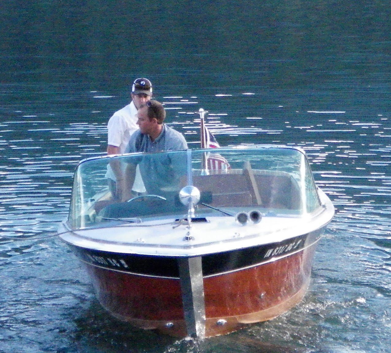 Two men are riding a boat with the license plate number nc 973