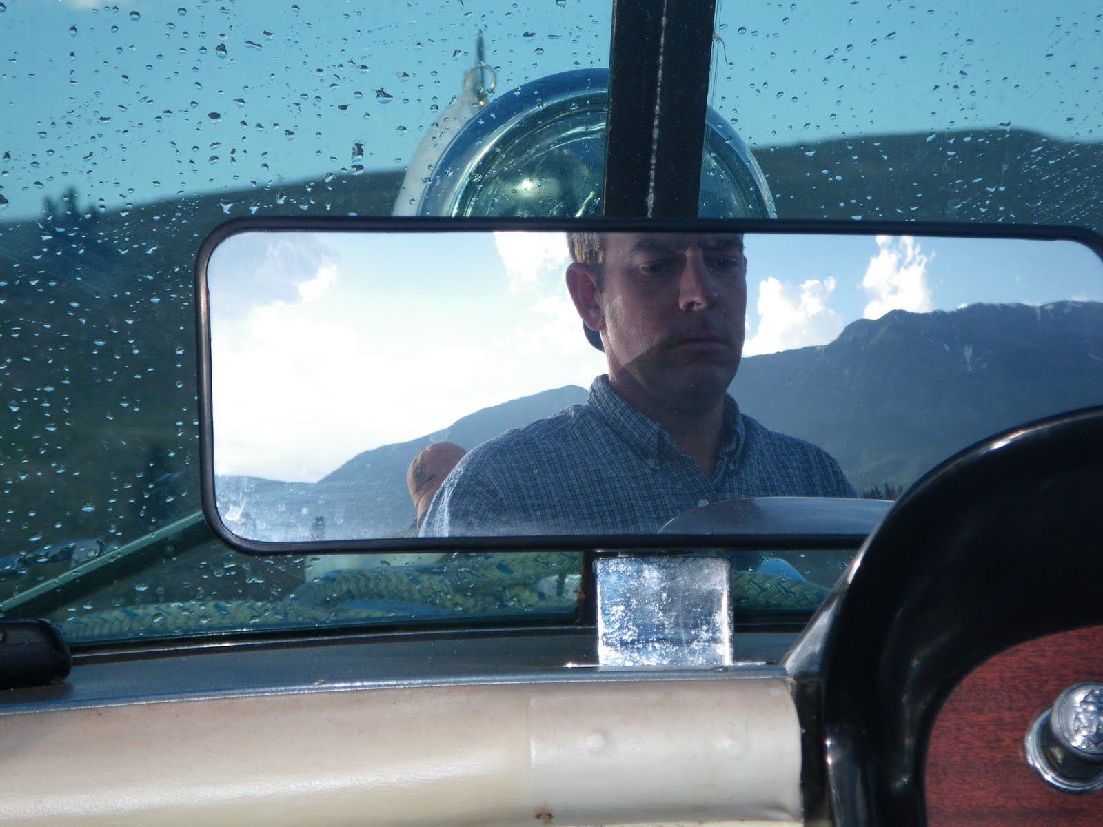 A man is reflected in the rear view mirror of a boat