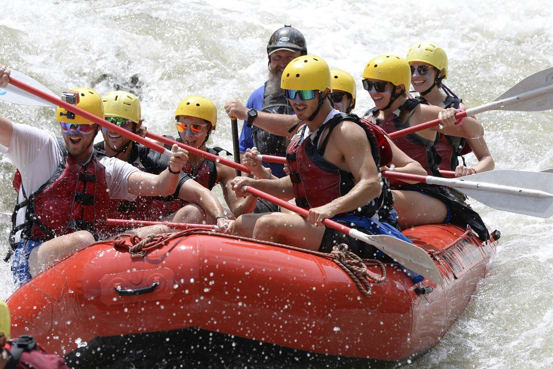 Group of People Rafting Down a River in A Red Raft