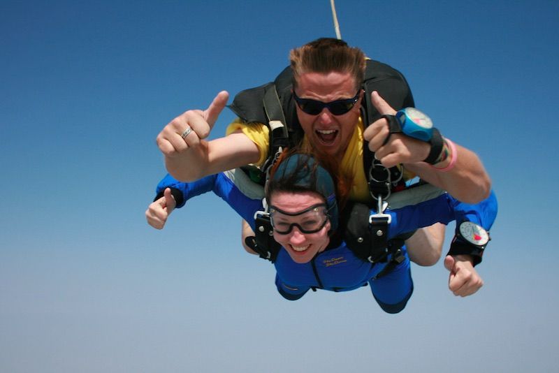 A man and a woman are flying through the air giving a thumbs up