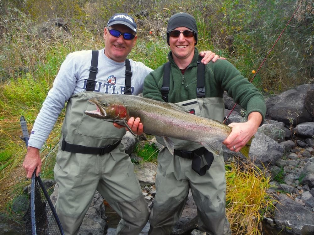 Two men standing next to each other holding a large fish