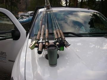 A white truck with fishing rods hanging from the hood