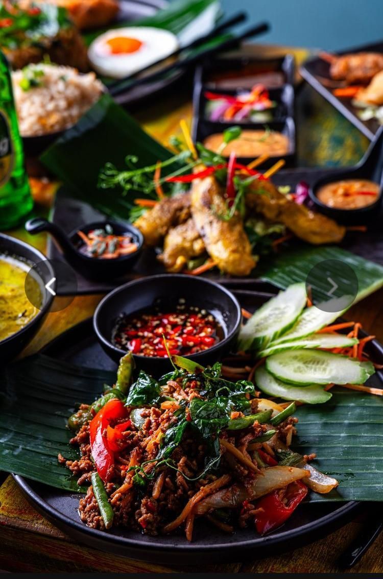Colorful Vietnamese-style meal with grilled meat, herbs, dipping sauces, and sliced cucumber on banana leaves