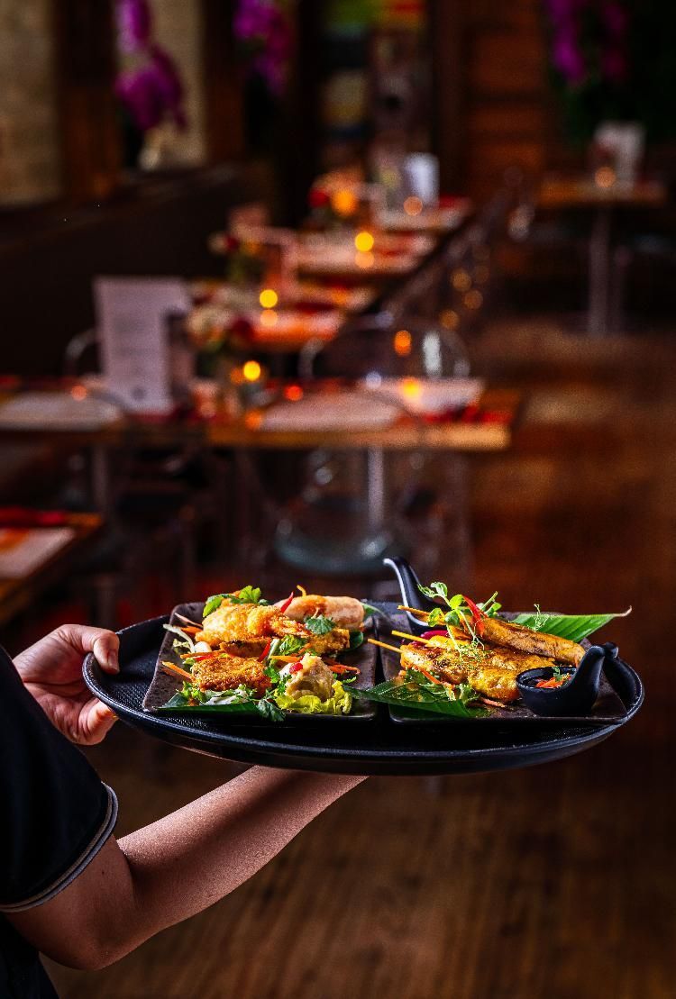 Waiter holding a tray of colorful plated appetizers in a dimly lit restaurant