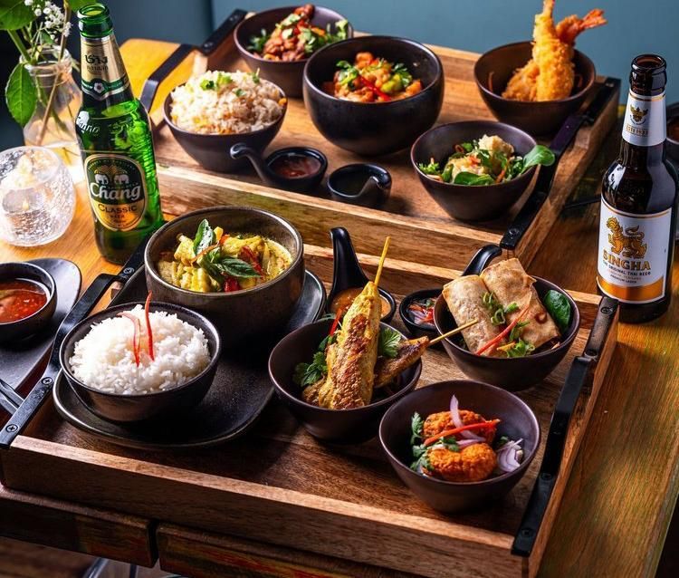 Assorted Japanese dishes and beer on wooden trays, with bowls of rice, curry, and fried food.
