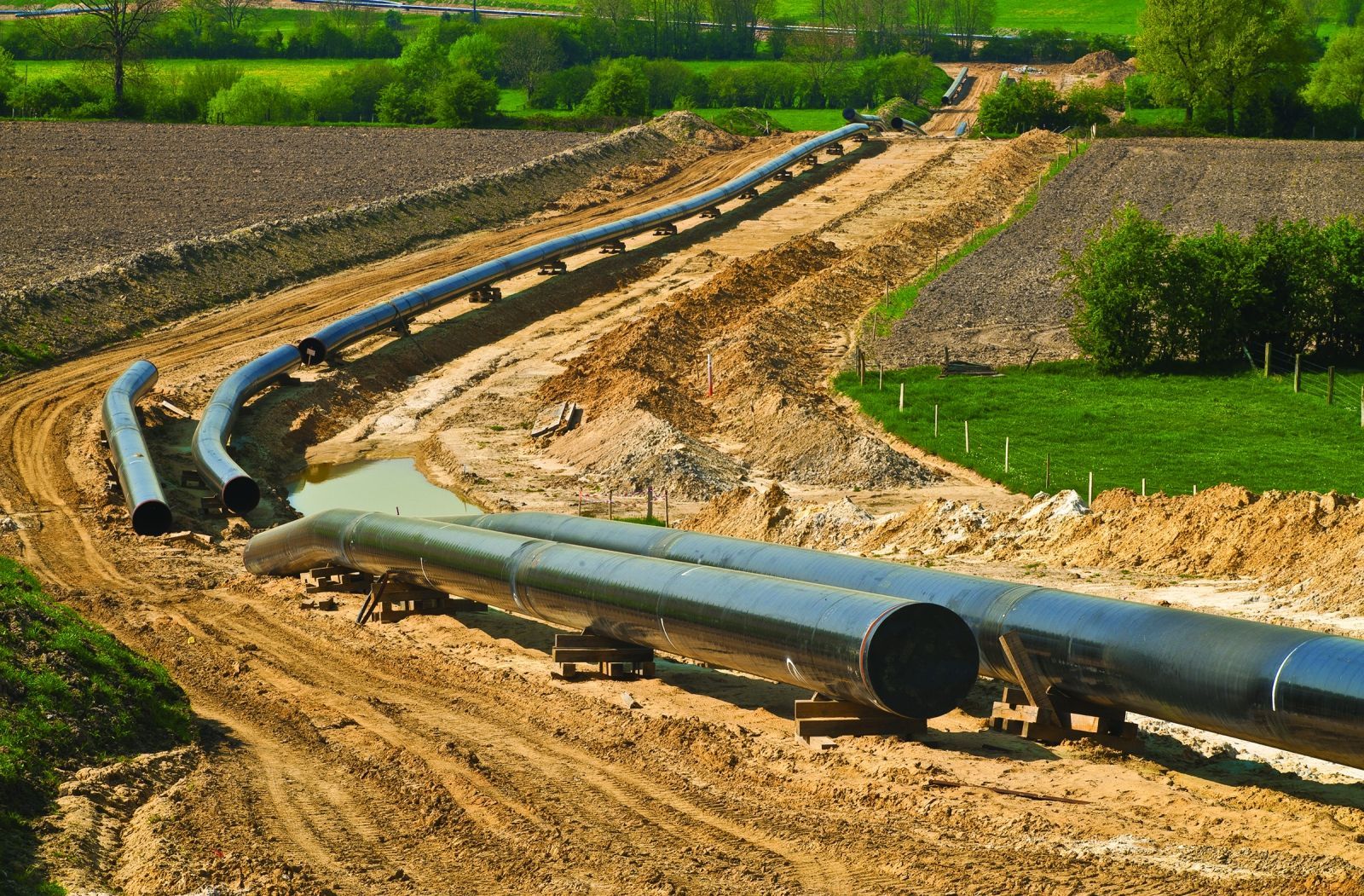 A pipeline is being built in the middle of a dirt road.