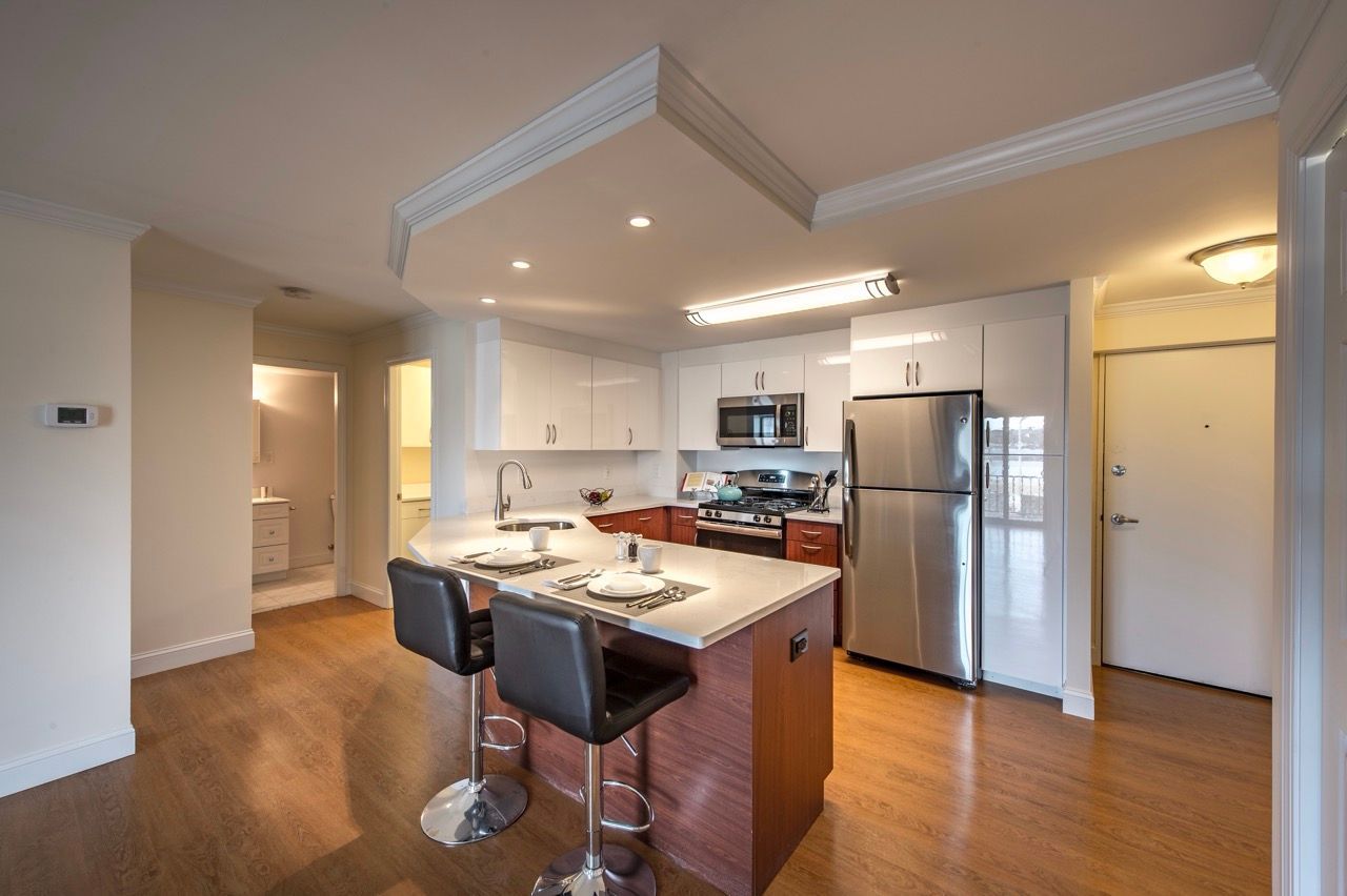 Open-concept kitchen with island, white cabinets, and stainless steel appliances.