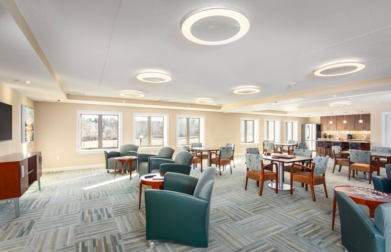 Spacious resident lounge with multiple seating areas and a kitchen in the background.