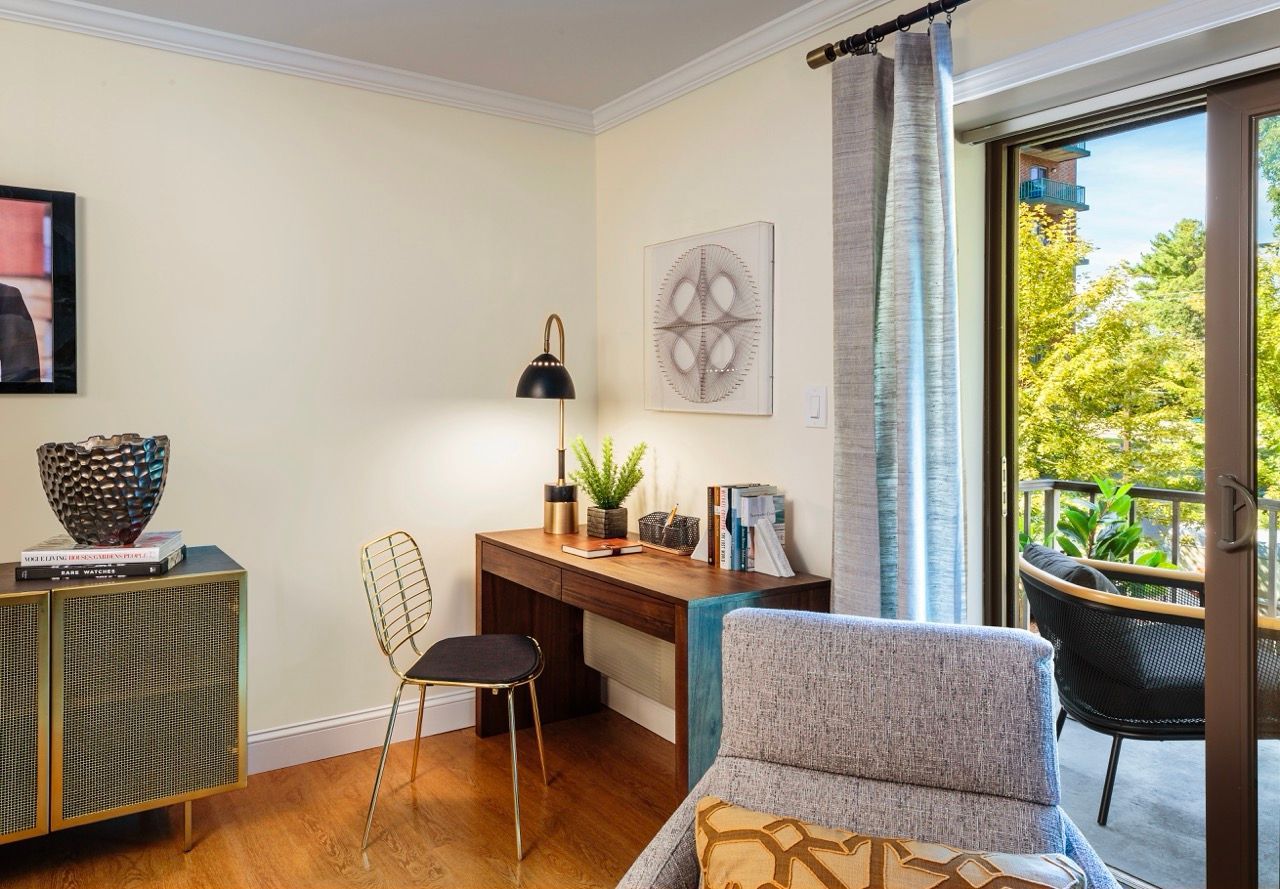 Modern apartment office area with desk, chair, and balcony door.