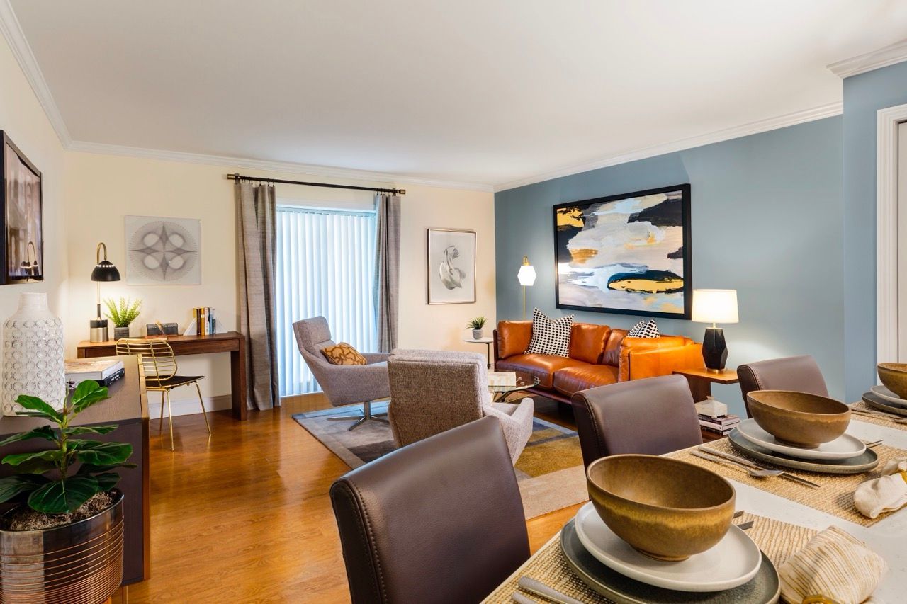 Living room in an apartment with blue accent wall, leather sofa, and dining set.