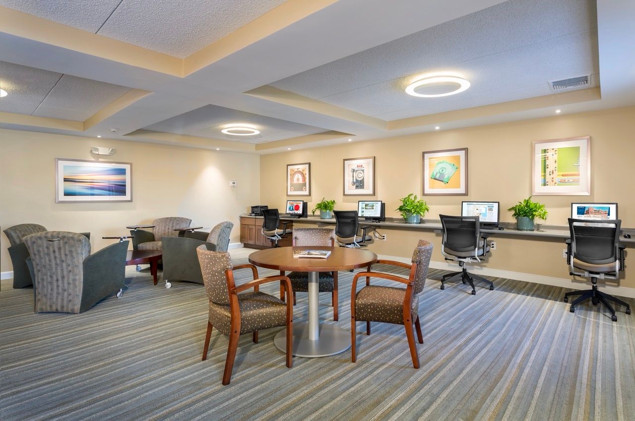 Interior of an apartment community lounge with computer workstations and seating.