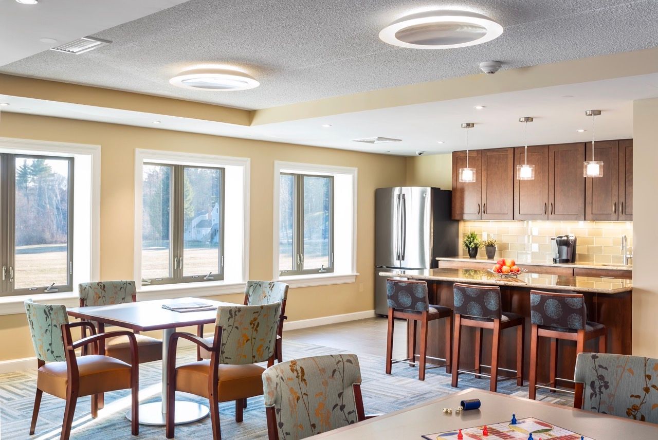 Bright community lounge with a kitchenette, island, and windows.