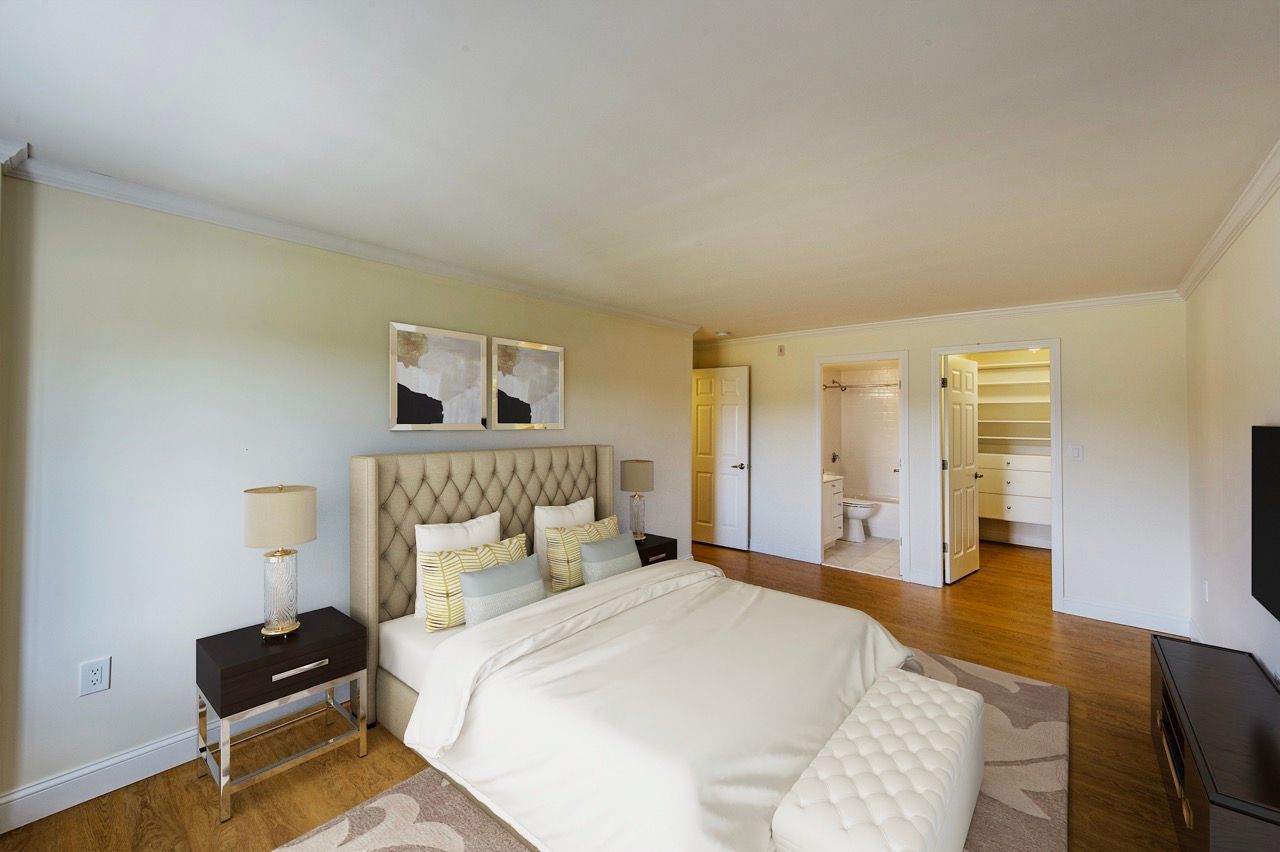 Bedroom with tufted headboard bed, two nightstands, and doors to a bathroom and closet.