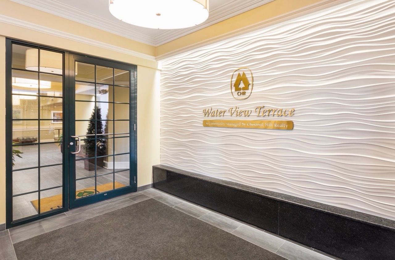 Lobby with glass doors, wave-textured wall, and gold Water View Terrace sign.