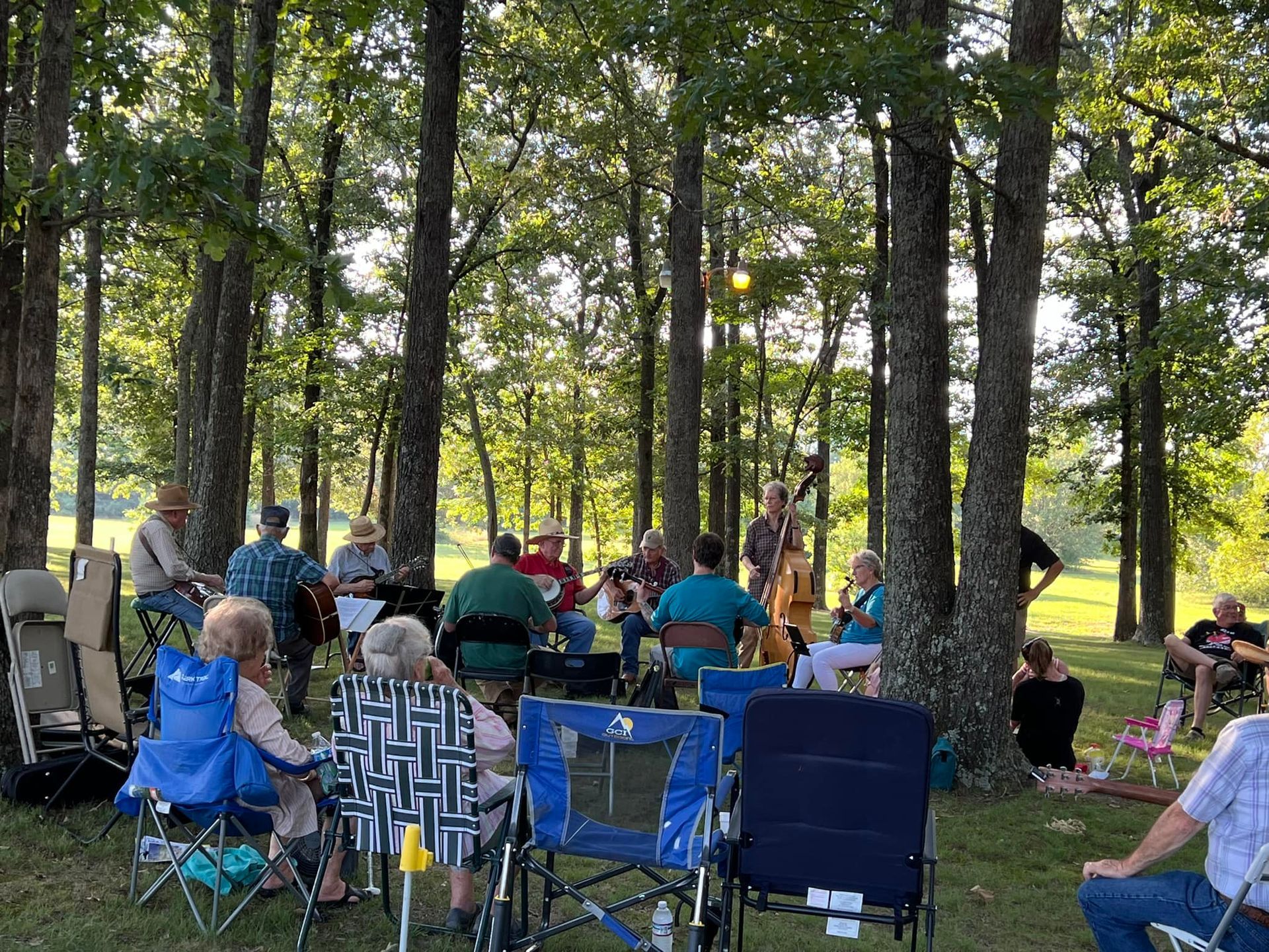 A group of people are sitting in chairs in the woods.