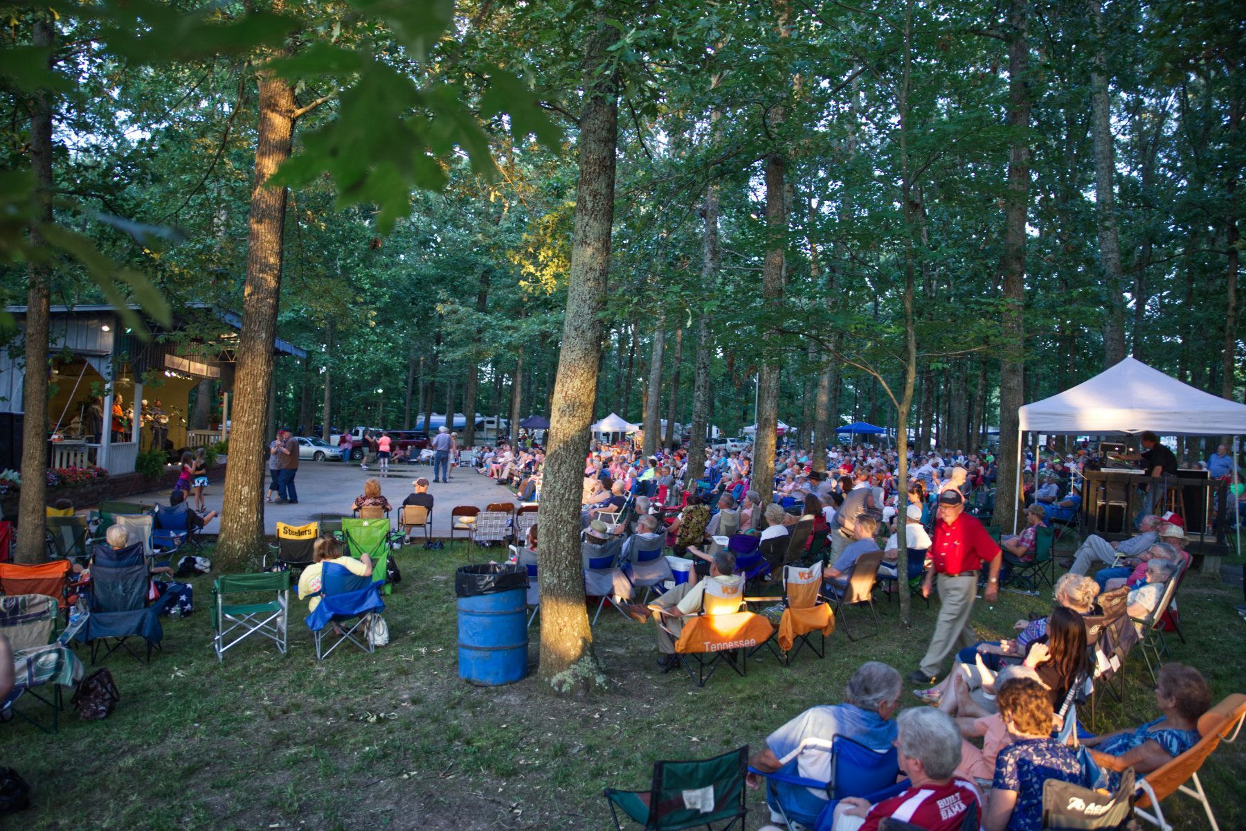 A large group of people are sitting in chairs in a park.