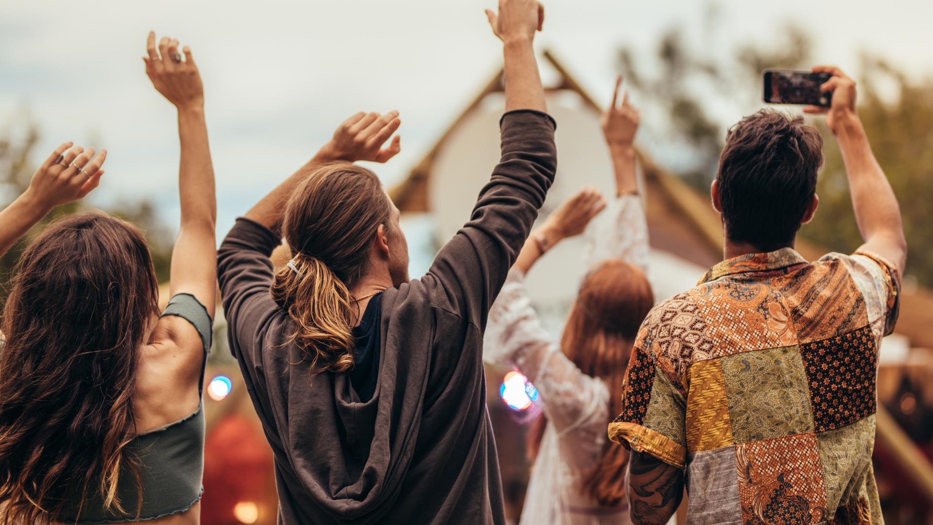 A group of people are raising their hands in the air at a concert.