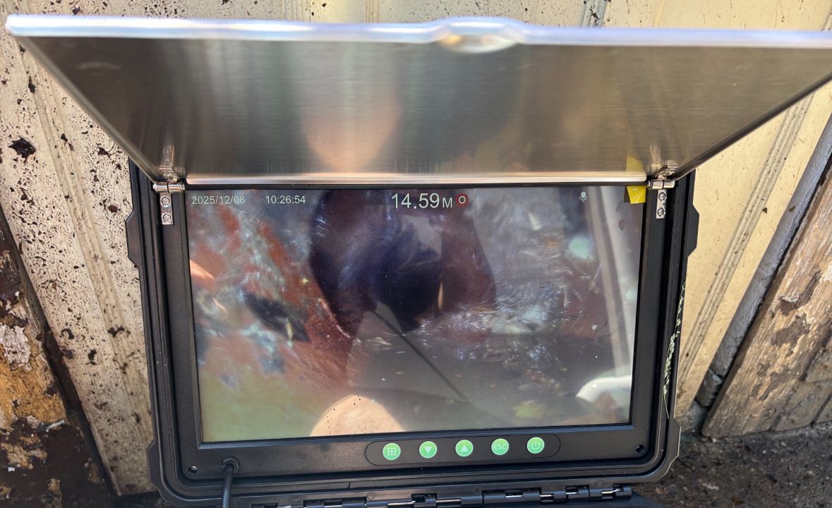 Monitor displaying internal view with a protective cover. Shows a reading of 14.5V. Mounted in a dirty environment.