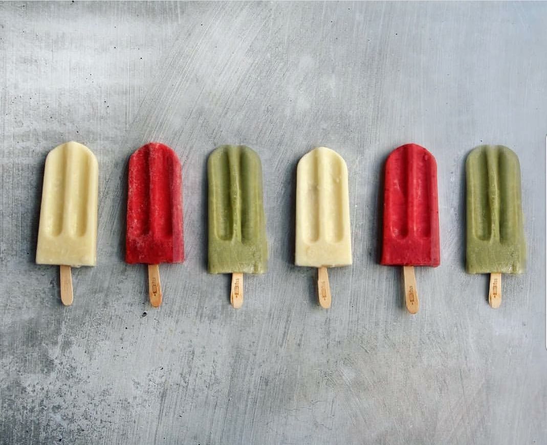 A row of colorful popsicles are lined up on a table