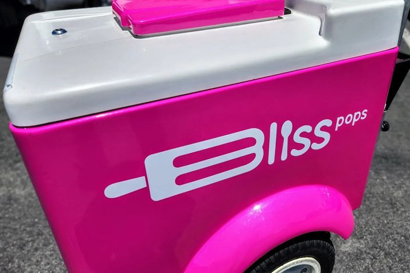 A pink and white cooler with bliss pops written on it