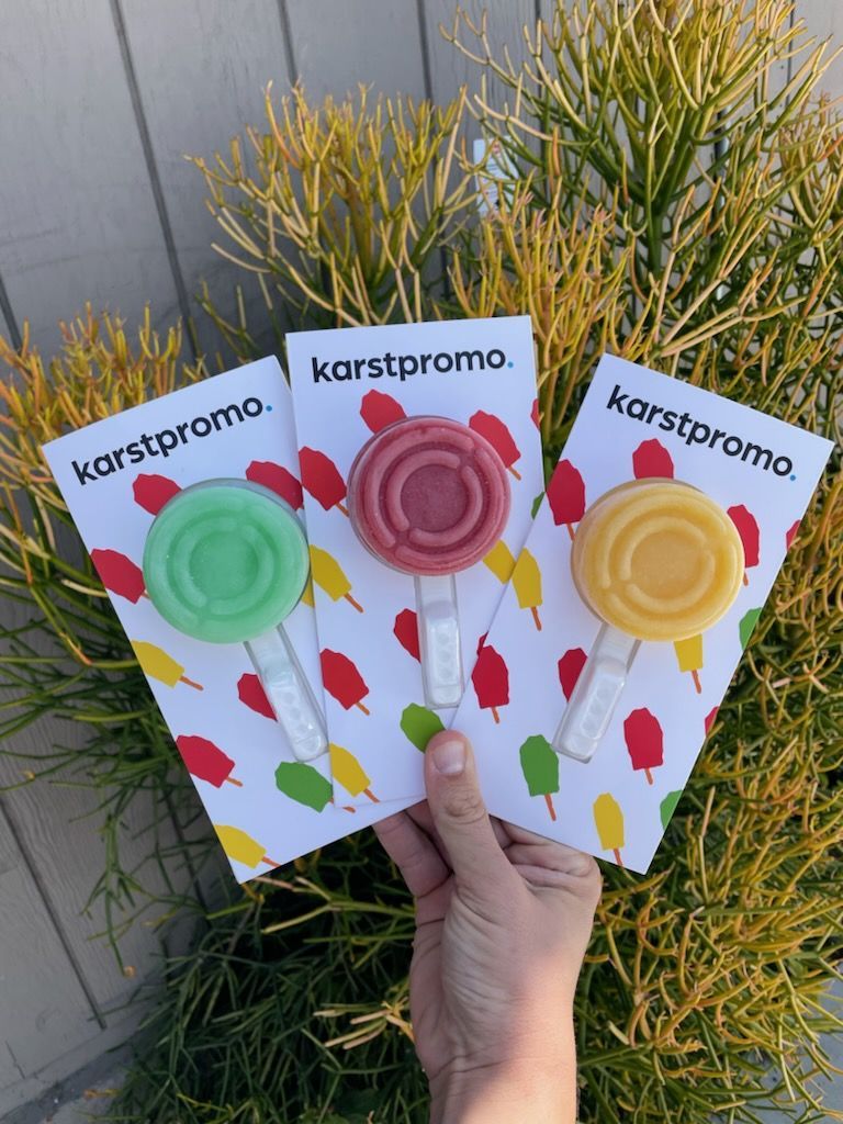 A person is holding three cards with lollipops on them.