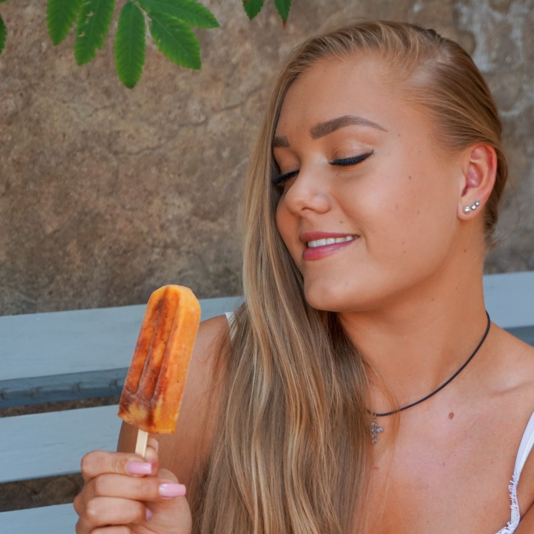 A woman is holding a popsicle in her hand and smiling