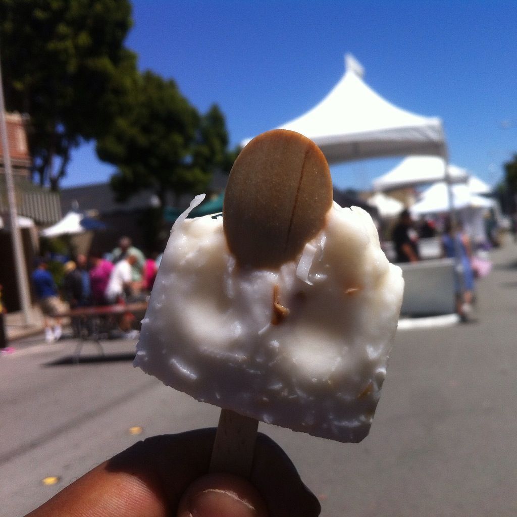 A person is holding an ice cream bar with a cookie on top