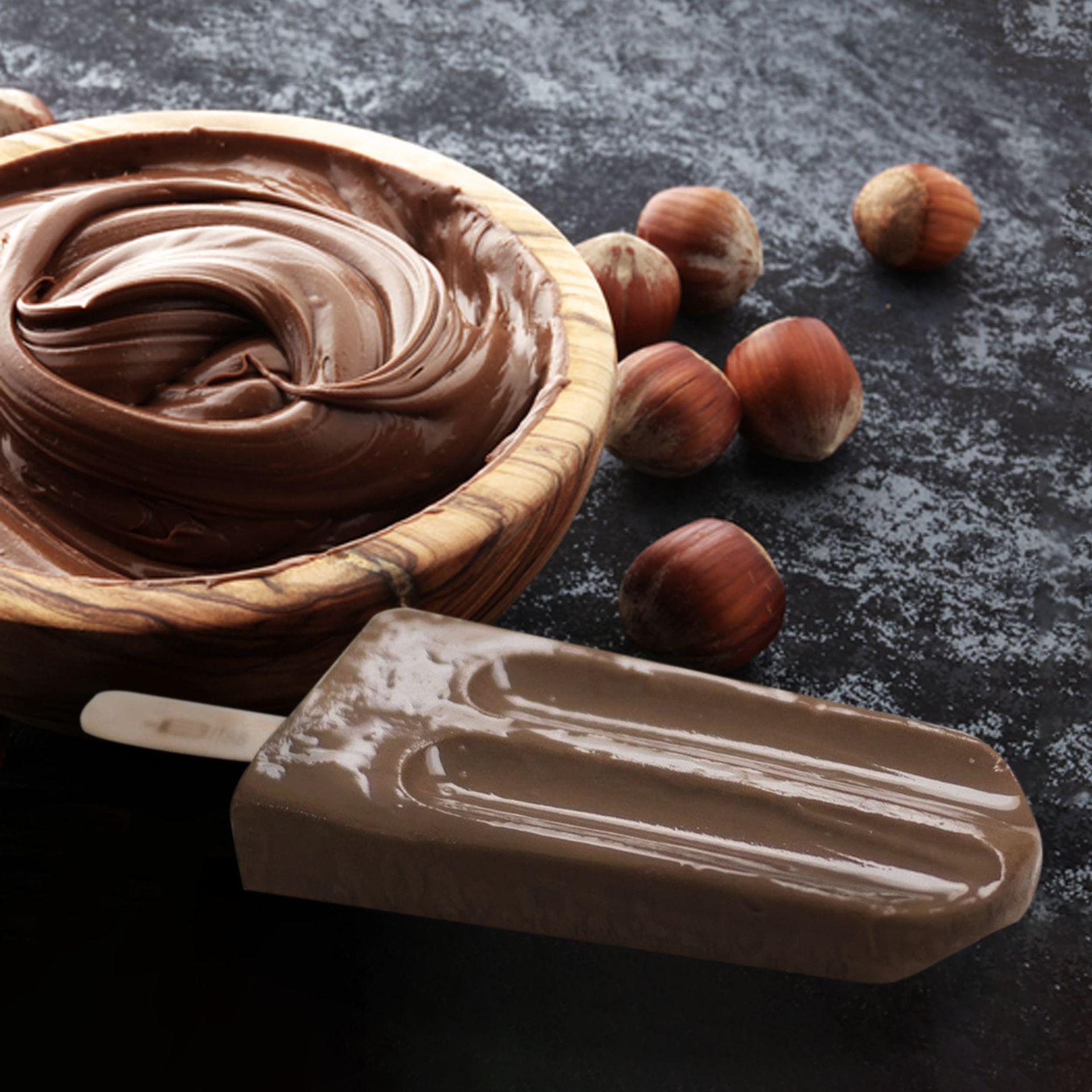 A popsicle next to a bowl of chocolate spread
