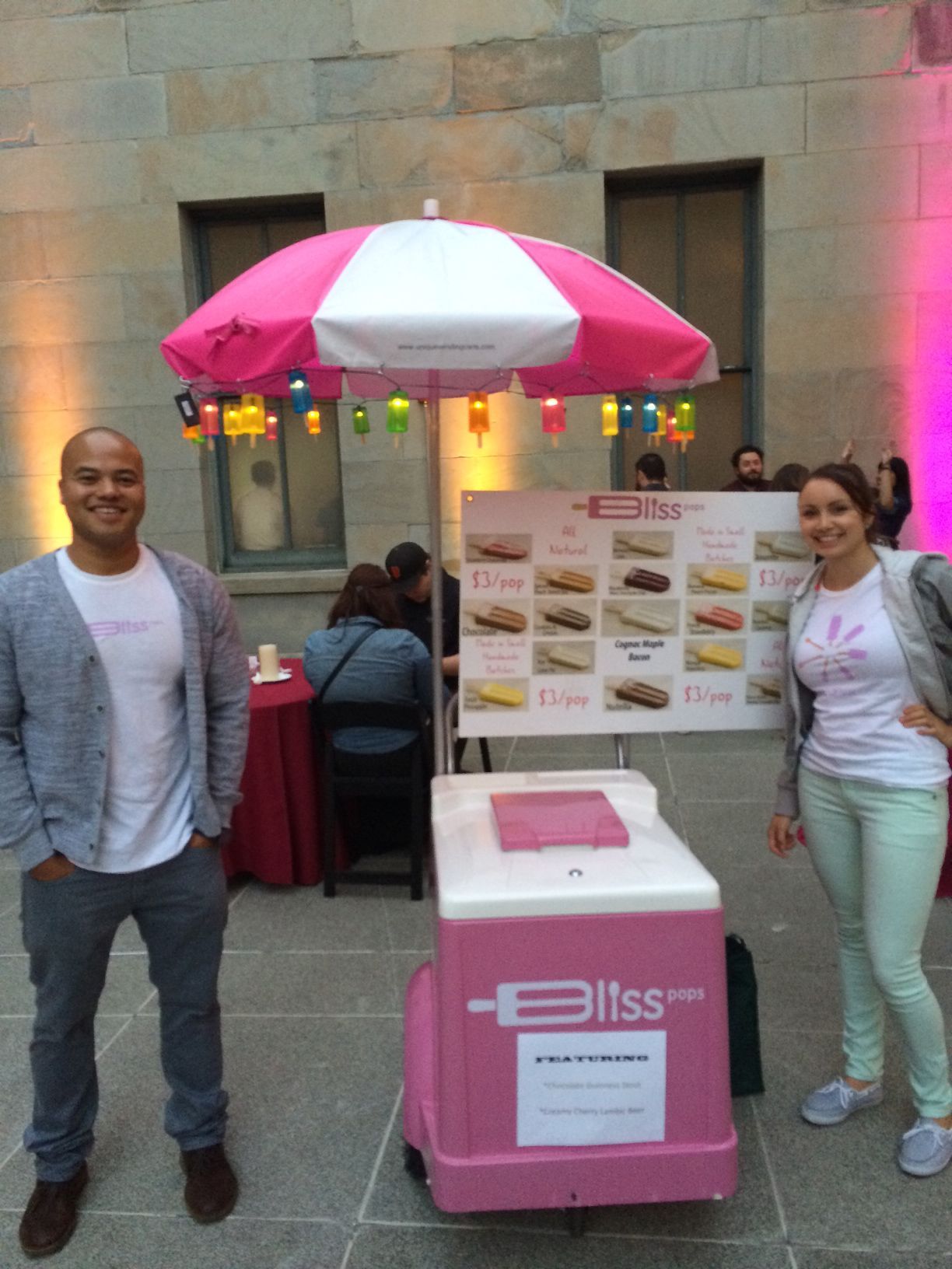 A man and a woman stand in front of a bliss ice cream cart