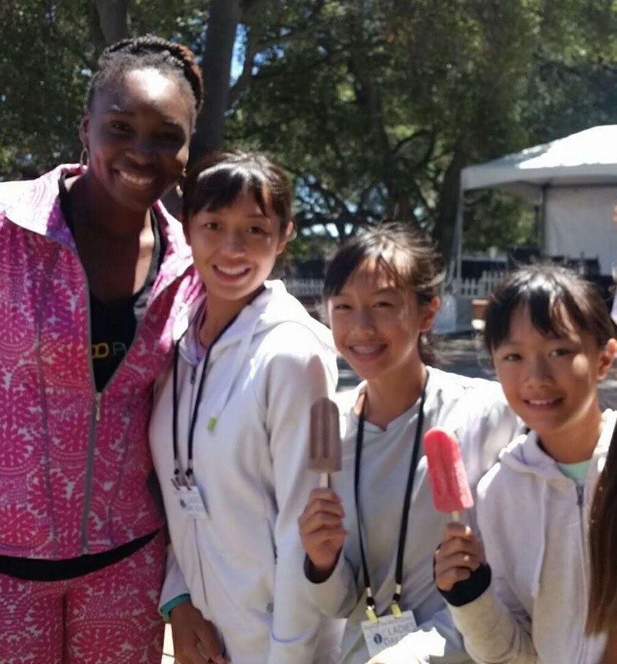 A group of young girls are posing for a picture while holding popsicles