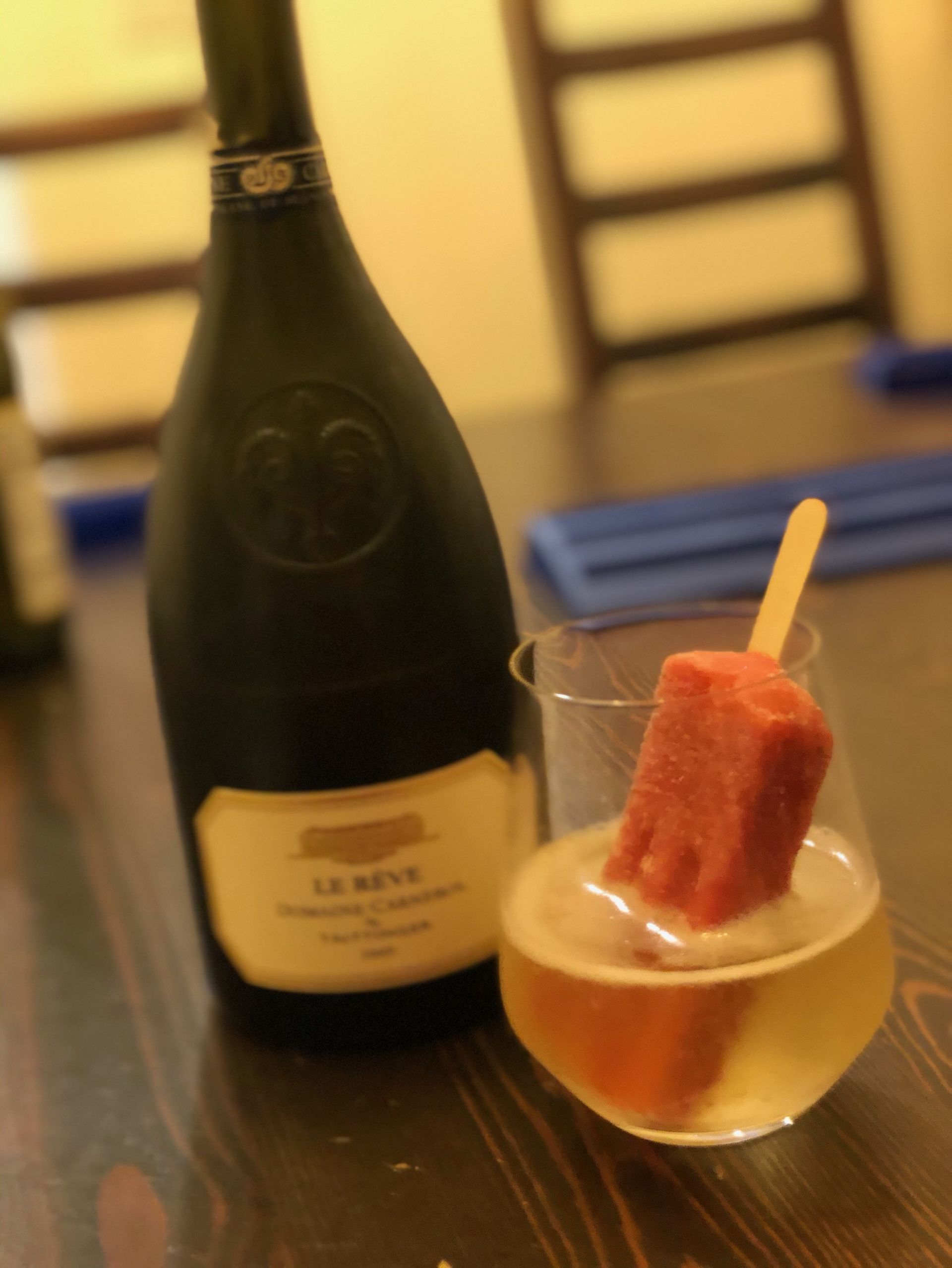 A bottle of le neuf is next to a glass of wine