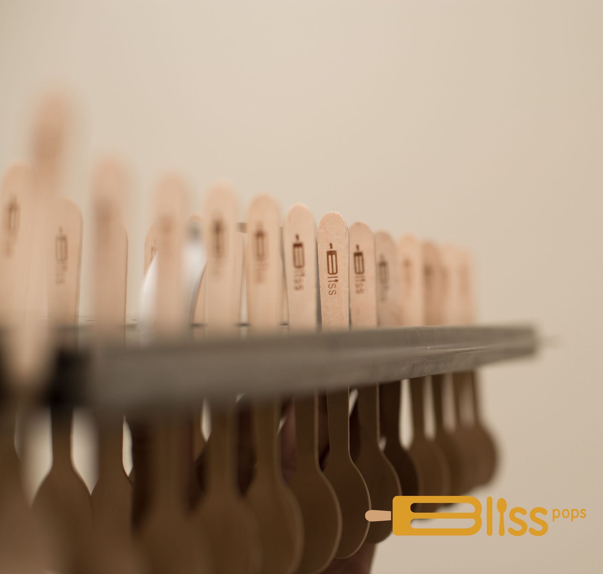 A row of wooden spoons are hanging on a rack.